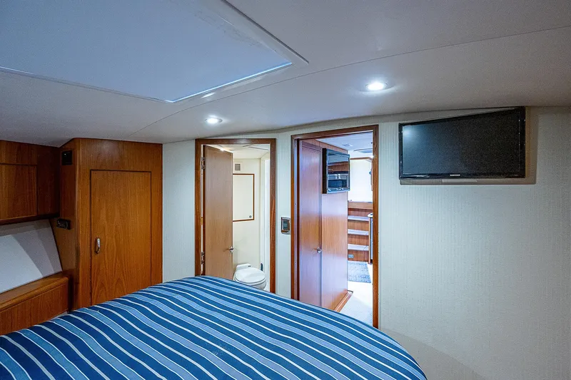 Slide: The Image of Interior of 2012 Cabo 44 HTX yacht bedroom with striped bedding and wall-mounted TV. - 14