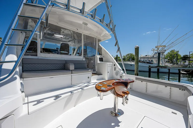 Slide: The Image of 2012 Cabo 44 HTX yacht cockpit with seating and fishing chair, docked under clear blue sky. - 47