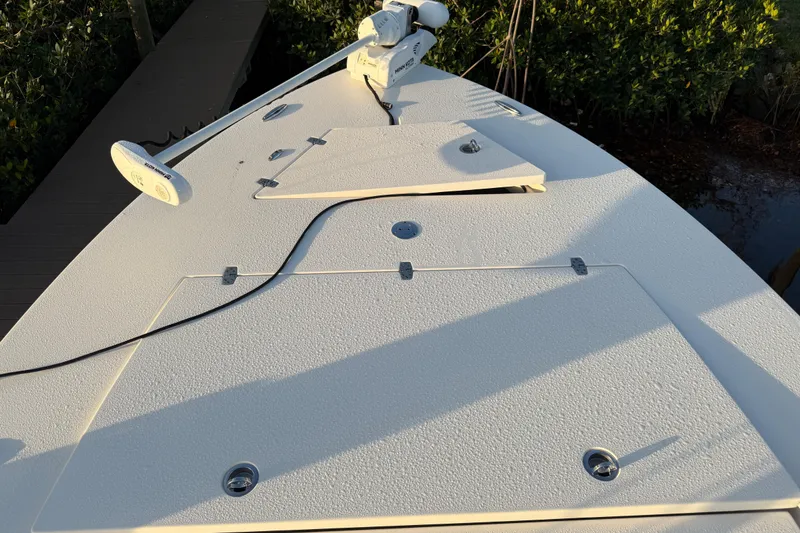 Slide: The Image of 2021 Hewes Redfisher 21 boat deck with trolling motor, docked near lush greenery. - 4