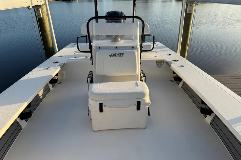 Slide: The Image of 2021 Hewes Redfisher 21 boat interior with seating, docked by calm water. - 5