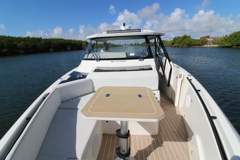 Slide: The Image of 2025 Saxdor 400 GTS boat interior with table, cruising on a scenic waterway. - 12