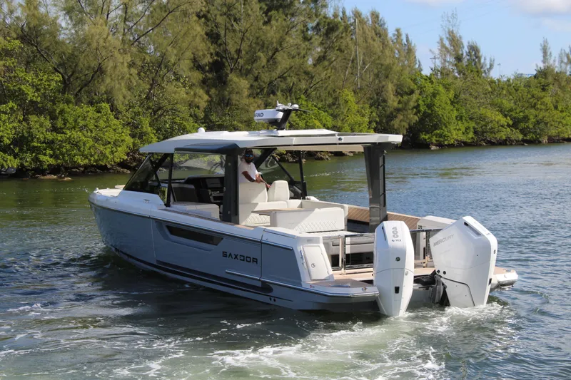 Slide: The Image of 2025 Saxdor 400 GTS boat cruising on a scenic waterway with lush greenery. - 32