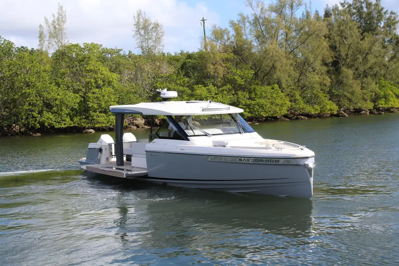 Slide: The Image of 2025 Saxdor 400 GTS boat cruising on a serene waterway surrounded by lush greenery. - 37