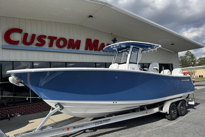 Slide: The Image of 2026 Sportsman Heritage 261 Center Console boat on trailer outside Custom Marine dealership. - 5