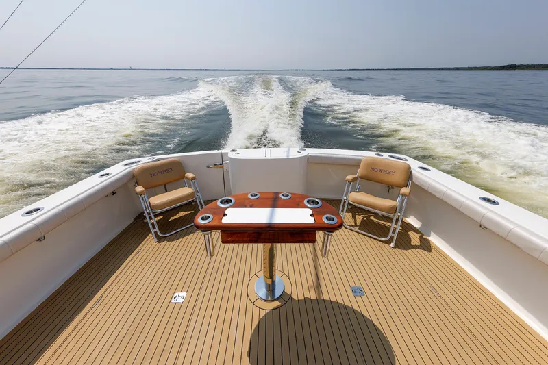 Slide: The Image of 2023 Henriques 42 Express Hardtop boat deck with chairs and table on open water. - 28