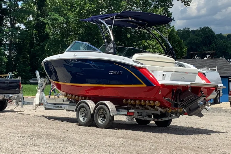 The Image of 2019 Cobalt R5 boat on trailer, vibrant red and blue design, parked outdoors. - 0