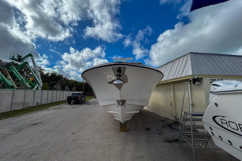 Slide: The Image of 2025 Robalo R300 Center Console boat parked outdoors under a cloudy sky. - 2