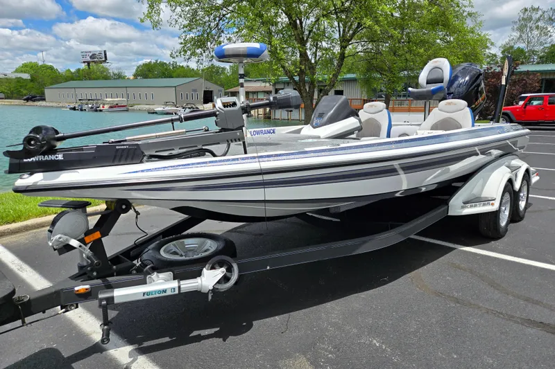 Slide: The Image of 2015 Skeeter FX20 bass boat on trailer in parking lot near lake. - 10