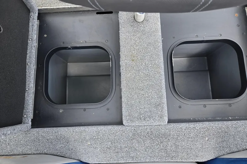 Slide: The Image of 2015 Skeeter FX20 boat storage compartments with gray carpeted interior. - 24