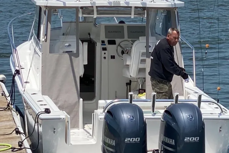 Slide: The Image of 2023 NorthCoast 255 Cabin boat with dual Yamaha engines at dock. - 2