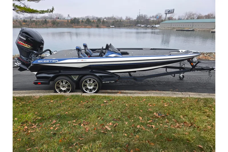 Slide: The Image of 2021 Skeeter FXR20 boat on trailer by a lake, featuring Yamaha engine. - 9
