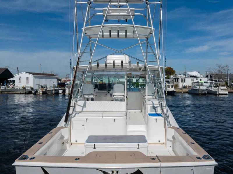 Slide: The Image of 2004 Cabo 40 Express boat docked at marina, featuring spacious deck and tower. - 10