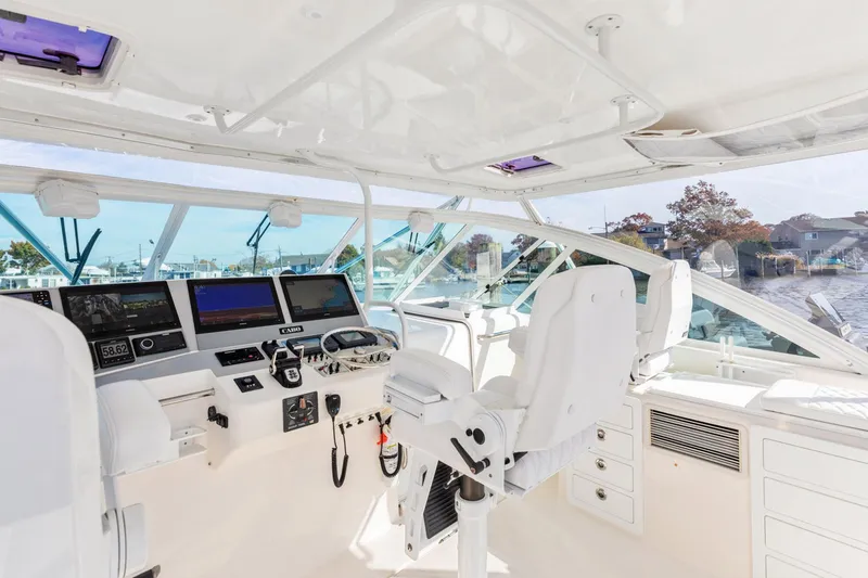 Slide: The Image of 2004 Cabo 40 Express yacht cockpit with modern navigation equipment and white seating. - 15