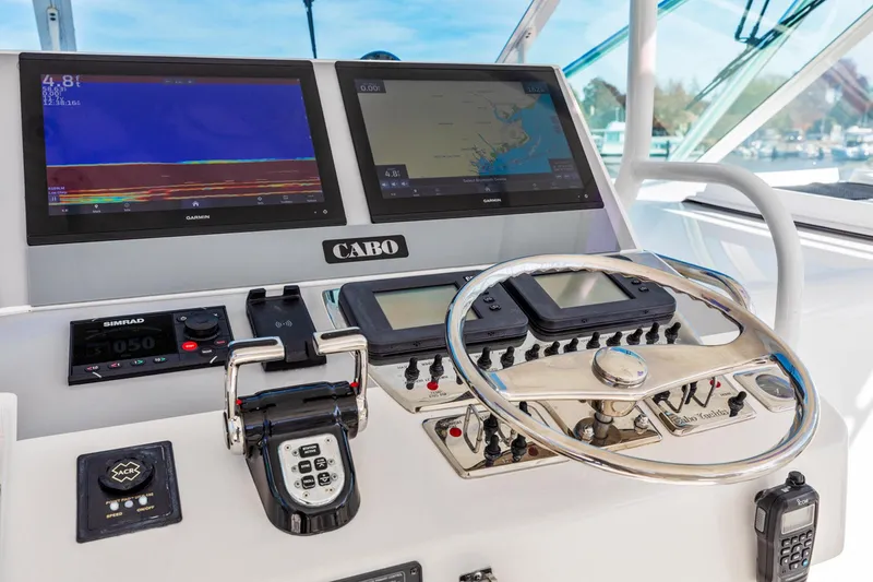 Slide: The Image of Control panel of 2004 Cabo 40 Express boat with navigation screens and steering wheel. - 16
