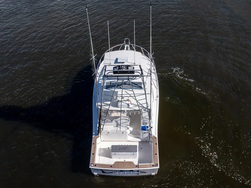 Slide: The Image of 2004 Cabo 40 Express boat on water, aerial view, showcasing fishing rods and spacious deck. - 2