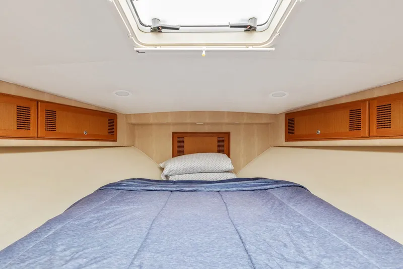 Slide: The Image of 2004 Cabo 40 Express cabin interior with bed and overhead storage. - 26