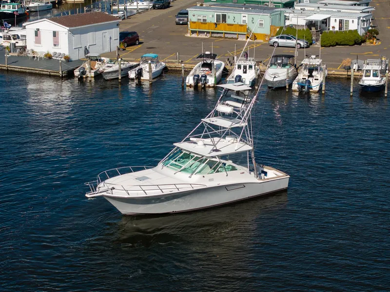 Slide: The Image of 2004 Cabo 40 Express boat docked in a marina, surrounded by other vessels. - 5