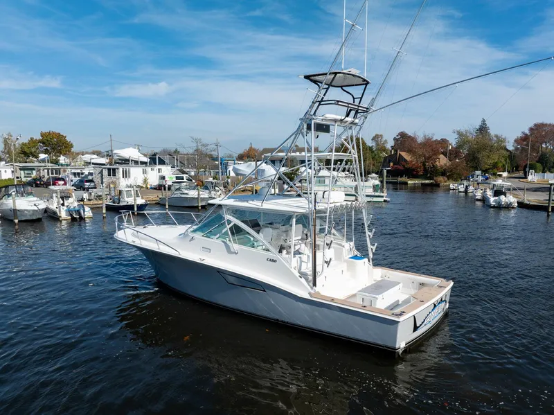 Slide: The Image of 2004 Cabo 40 Express boat docked in a marina under a clear blue sky. - 7