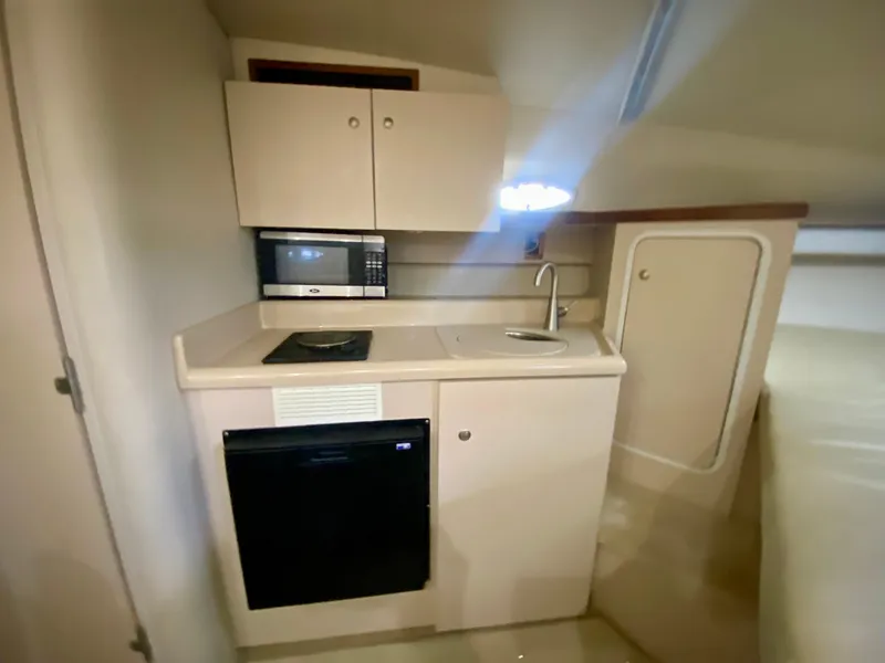 Slide: The Image of 1999 Cruisers Yachts 2870 Express cabin kitchen with microwave, sink, and storage. - 11