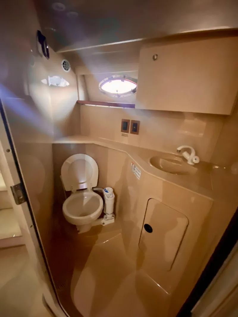 Slide: The Image of 1999 Cruisers Yachts 2870 Express bathroom with toilet, sink, and storage cabinet. - 12