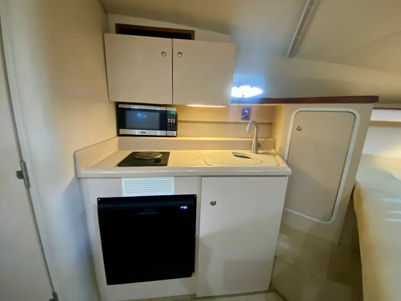 Slide: The Image of 1999 Cruisers Yachts 2870 Express kitchenette with microwave, sink, and compact fridge. - 18