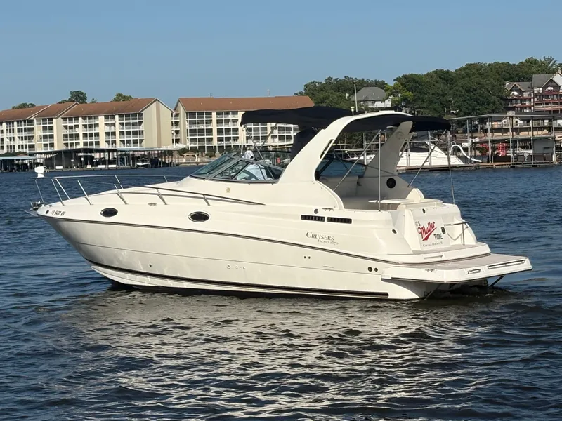 Slide: The Image of 1999 Cruisers Yachts 2870 Express boat on a calm lake near waterfront buildings. - 3