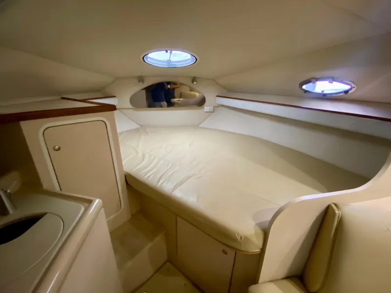 Slide: The Image of 1999 Cruisers Yachts 2870 Express cabin interior with bed and portholes. - 9