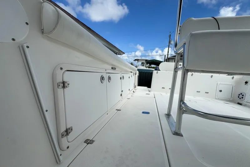 Slide: The Image of Century 3200 Center Console 2000 boat interior with storage compartments and seating, under a clear blue sky. - 38
