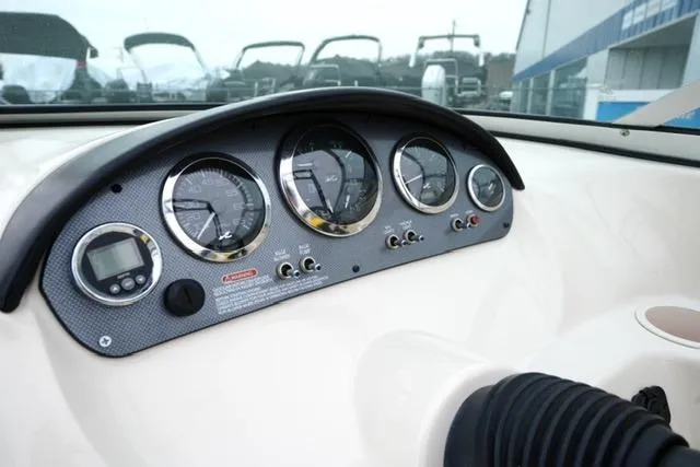 Slide: The Image of 2006 Sea Ray 205 Sport dashboard with gauges and controls in a marina setting. - 13