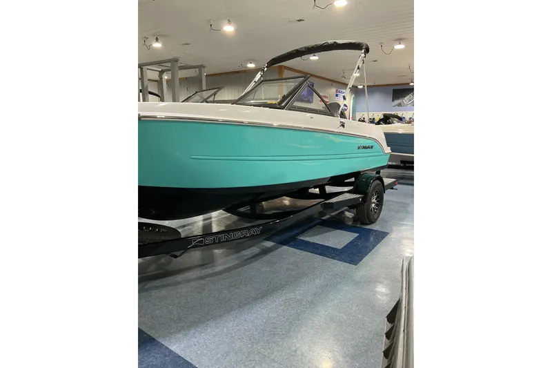 Slide: The Image of 2026 Stingray 172 DC boat in showroom, turquoise hull, on trailer. - 3