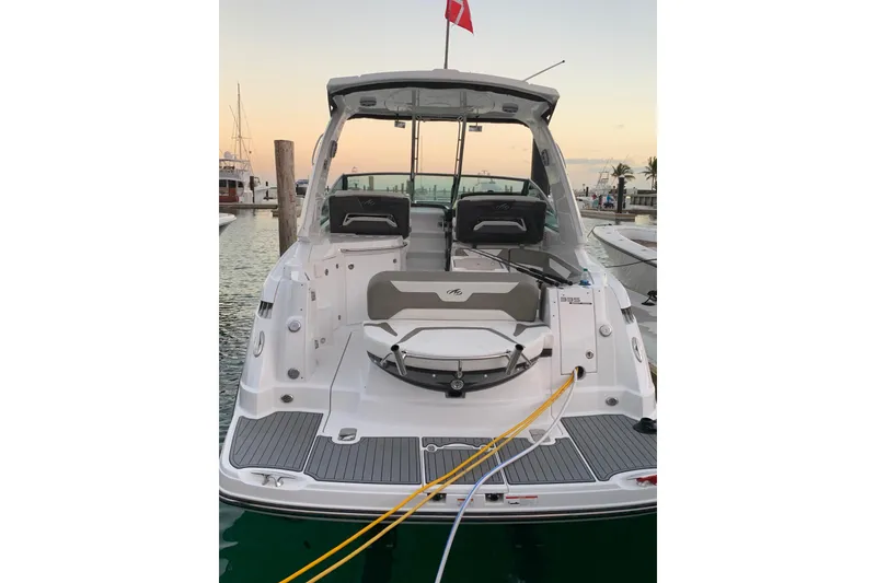Slide: The Image of 2018 Monterey 335 Sport Yacht docked at sunset, rear view with seating and flag. - 2
