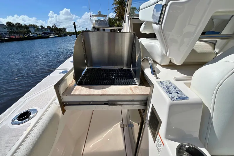 Slide: The Image of 2019 Pursuit S 368 Sport boat with built-in grill on deck, docked by water. - 19