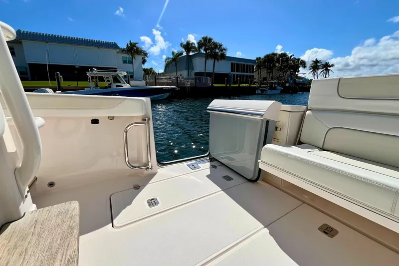 Slide: The Image of 2019 Pursuit S 368 Sport boat interior with seating, docked by waterfront buildings. - 23