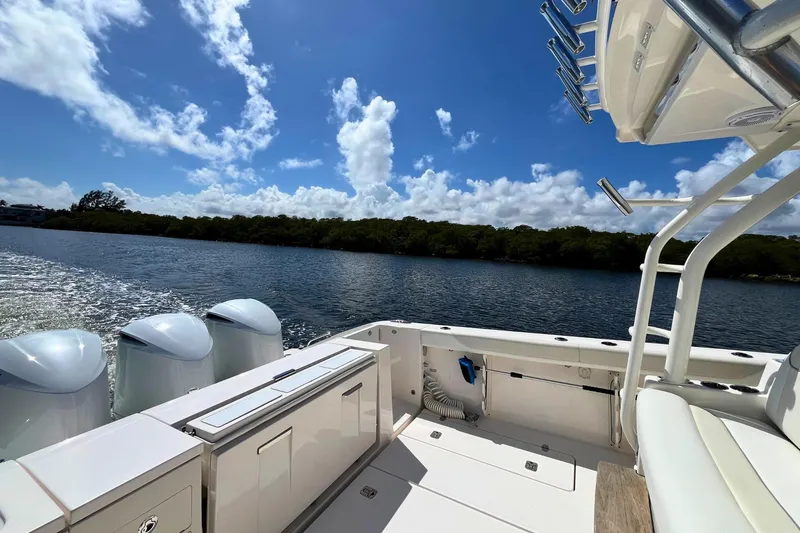 Slide: The Image of 2019 Pursuit S 368 Sport boat on water, clear sky, lush shoreline in background. - 24