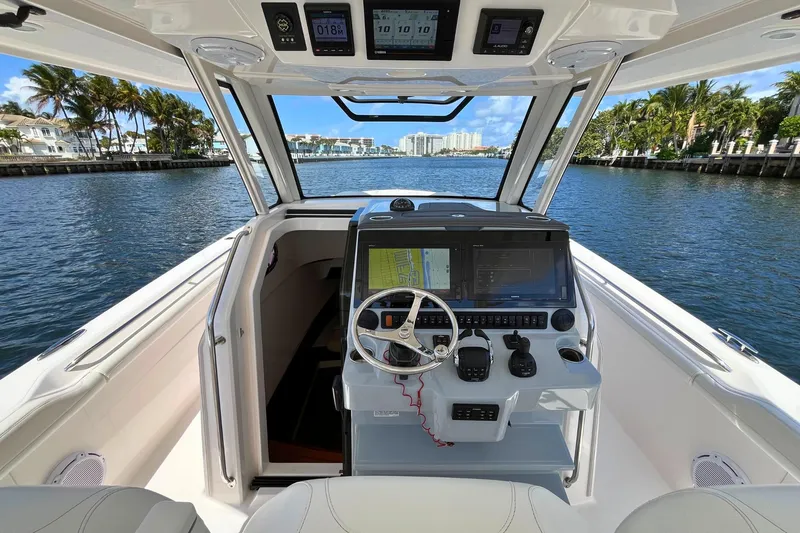 Slide: The Image of 2019 Pursuit S 368 Sport boat cockpit with navigation system, steering wheel, and waterfront view. - 3