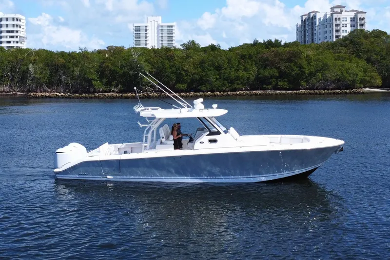 Slide: The Image of 2019 Pursuit S 368 Sport boat cruising on a calm waterway with lush greenery. - 37