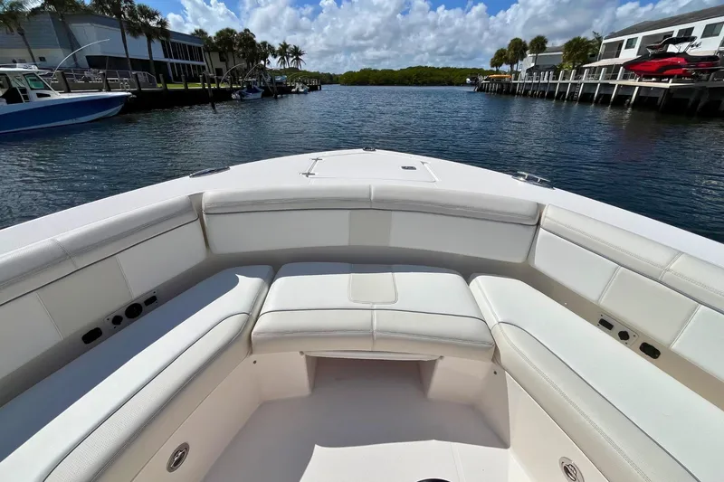 Slide: The Image of 2019 Pursuit S 368 Sport boat with spacious seating, docked by a scenic waterfront. - 9