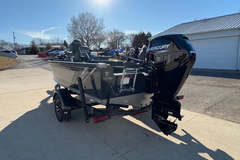 Slide: The Image of 2025 Lund 1875 Pro Guide boat with Mercury engine on a trailer in a driveway. - 3