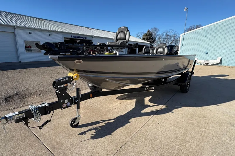 Slide: The Image of 2025 Lund 1875 Pro Guide boat on trailer outside showroom, sunny day. - 5