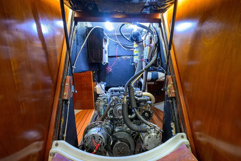 Slide: The Image of Engine room of a 2003 Beneteau 50 yacht, showcasing mechanical components and wooden paneling. - 24