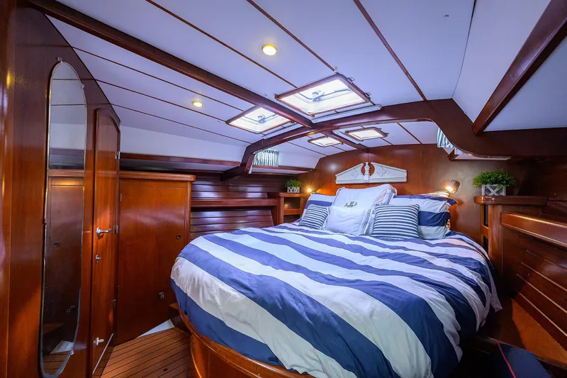 Slide: The Image of Luxurious cabin interior of 2003 Beneteau 50 yacht with striped bedding and wooden finish. - 52