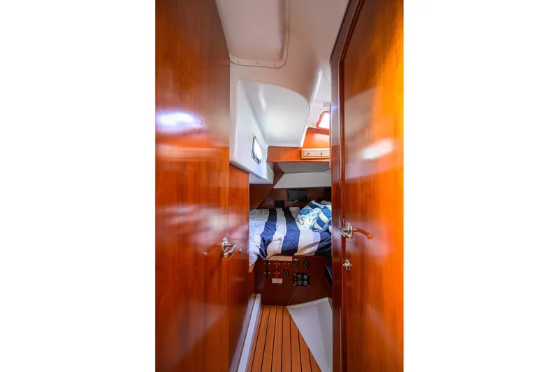 Slide: The Image of Cozy cabin interior of 2003 Beneteau 50 yacht with wooden finish and striped bedding. - 67