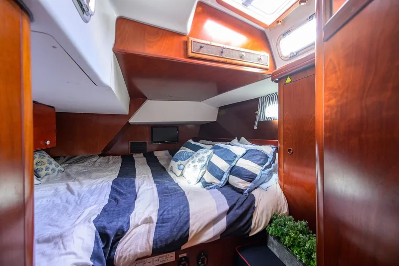 Slide: The Image of Cozy cabin interior of 2003 Beneteau 50 yacht with striped bedding and wooden finish. - 68