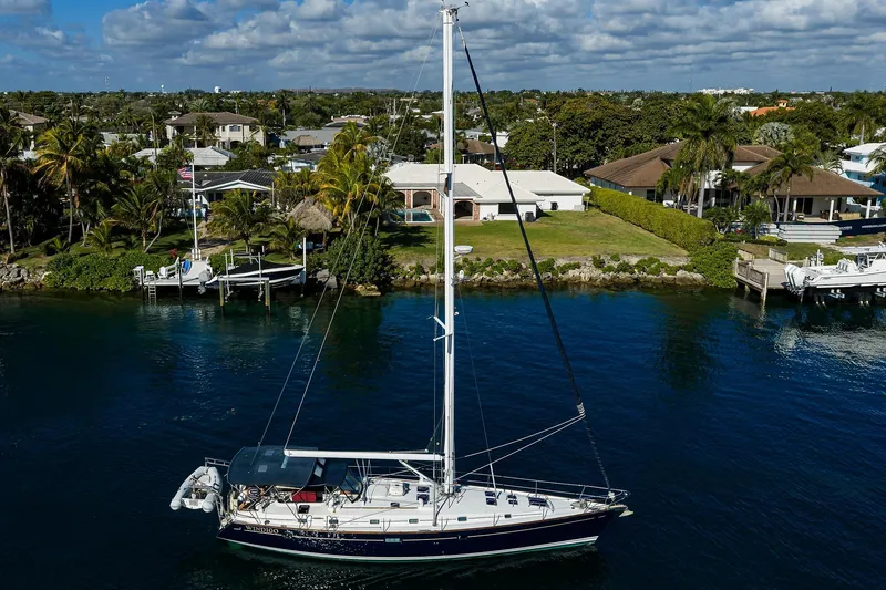 Slide: The Image of Sailboat Beneteau 50 (2003) cruising near waterfront homes under a partly cloudy sky. - 73