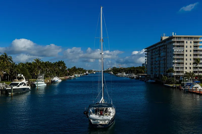 Slide: The Image of Sailboat Beneteau 50 (2003) cruising a scenic canal with palm trees and buildings. - 80