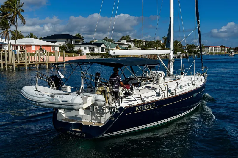 Slide: The Image of Sailing yacht Beneteau 50, 2003 model, cruising near waterfront homes under a clear blue sky. - 82