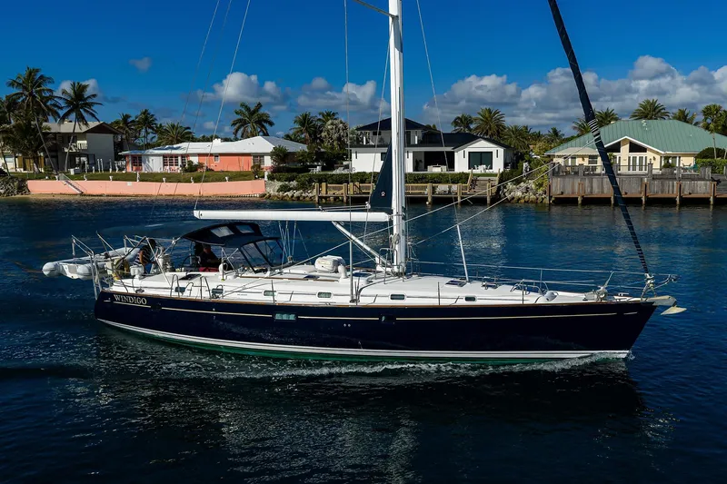 Slide: The Image of 2003 Beneteau 50 sailboat cruising near waterfront homes under a clear blue sky. - 89