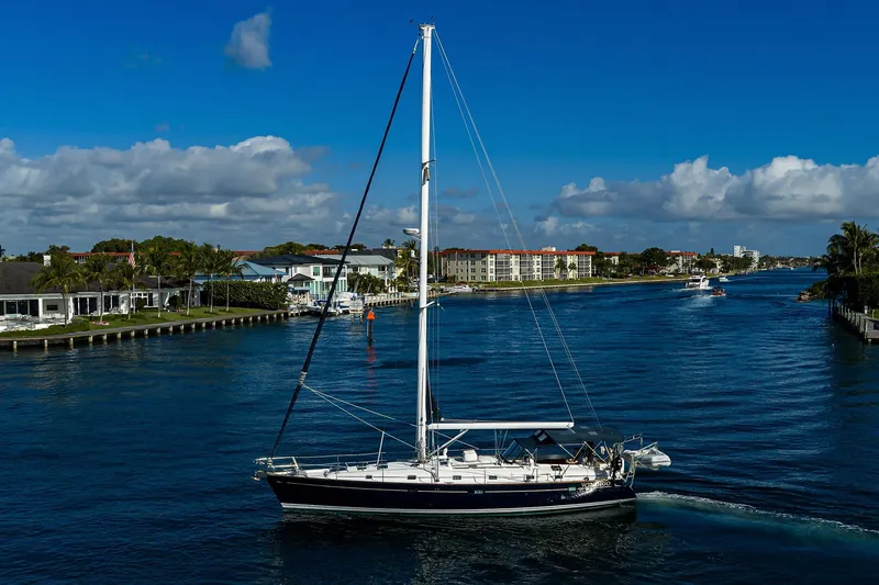 Slide: The Image of Sailing yacht Beneteau 50 (2003) cruising on a scenic waterway under a clear blue sky. - 90