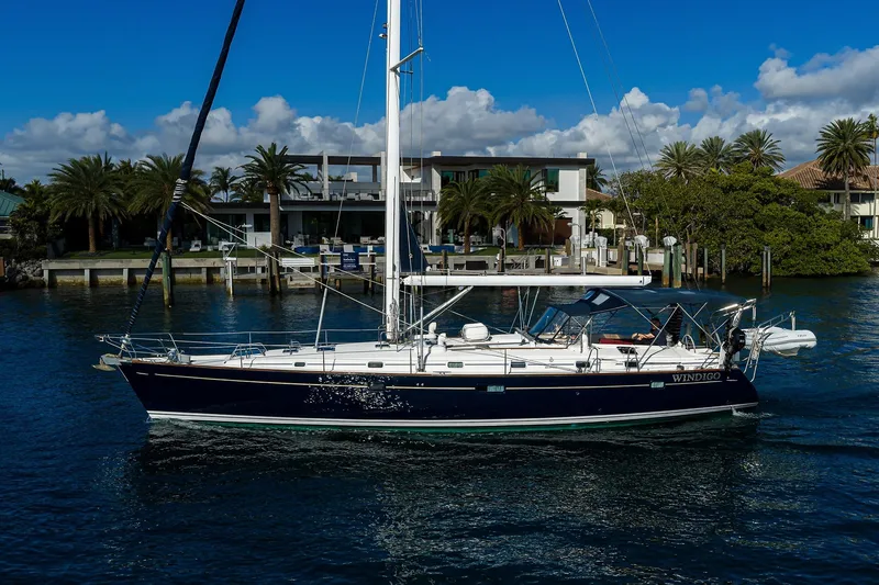 Slide: The Image of 2003 Beneteau 50 sailboat on water, with palm trees and modern houses in the background. - 92