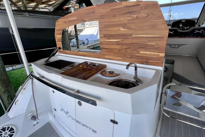 Slide: The Image of 2024 NX Boats 370 HT featuring a sleek outdoor kitchenette with wooden accents and modern amenities. - 16